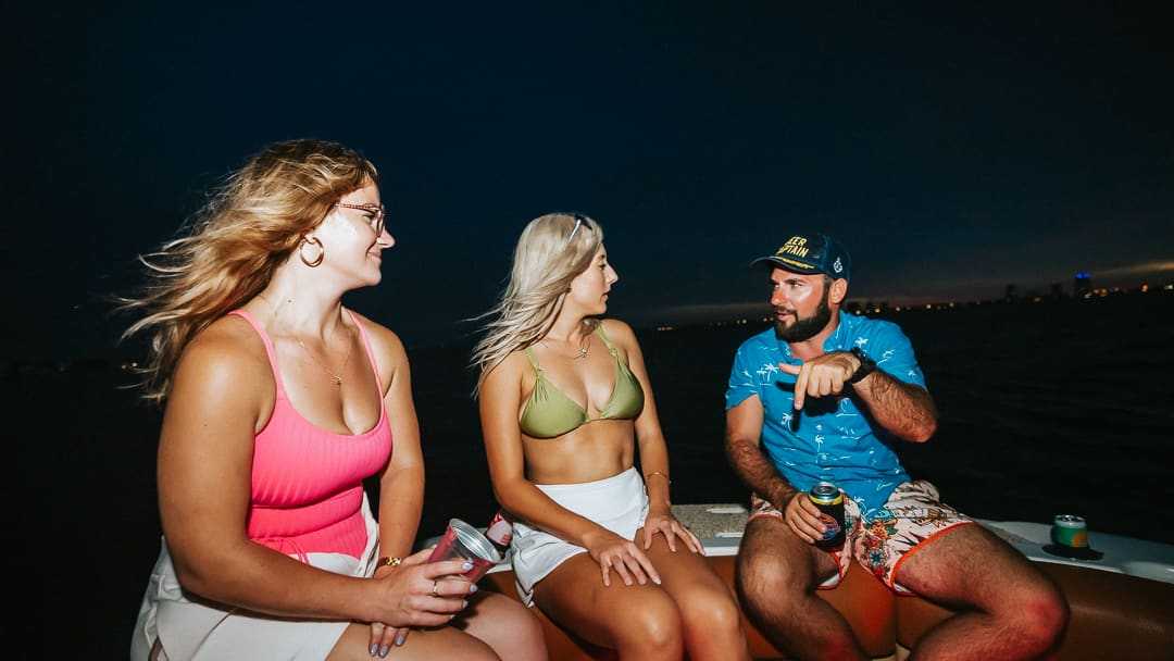 Captain talking with guests on the bow as night falls over Tampa Bay.