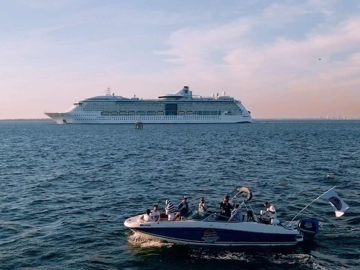 Private charter cruising past a cruise ship in the open waters of Tampa Bay.