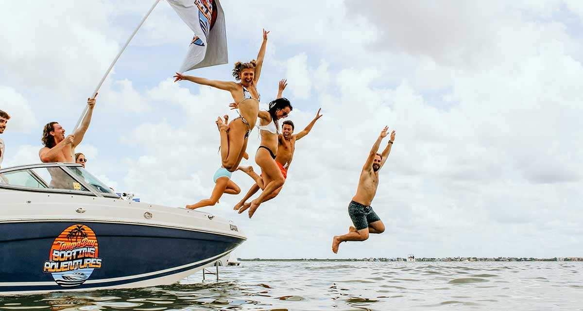 Friends jumping off a party boat into the water near Tampa Bay, FL.
