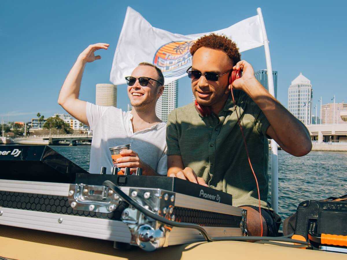 DJs mixing on the boat deck with the Tampa skyline behind them.