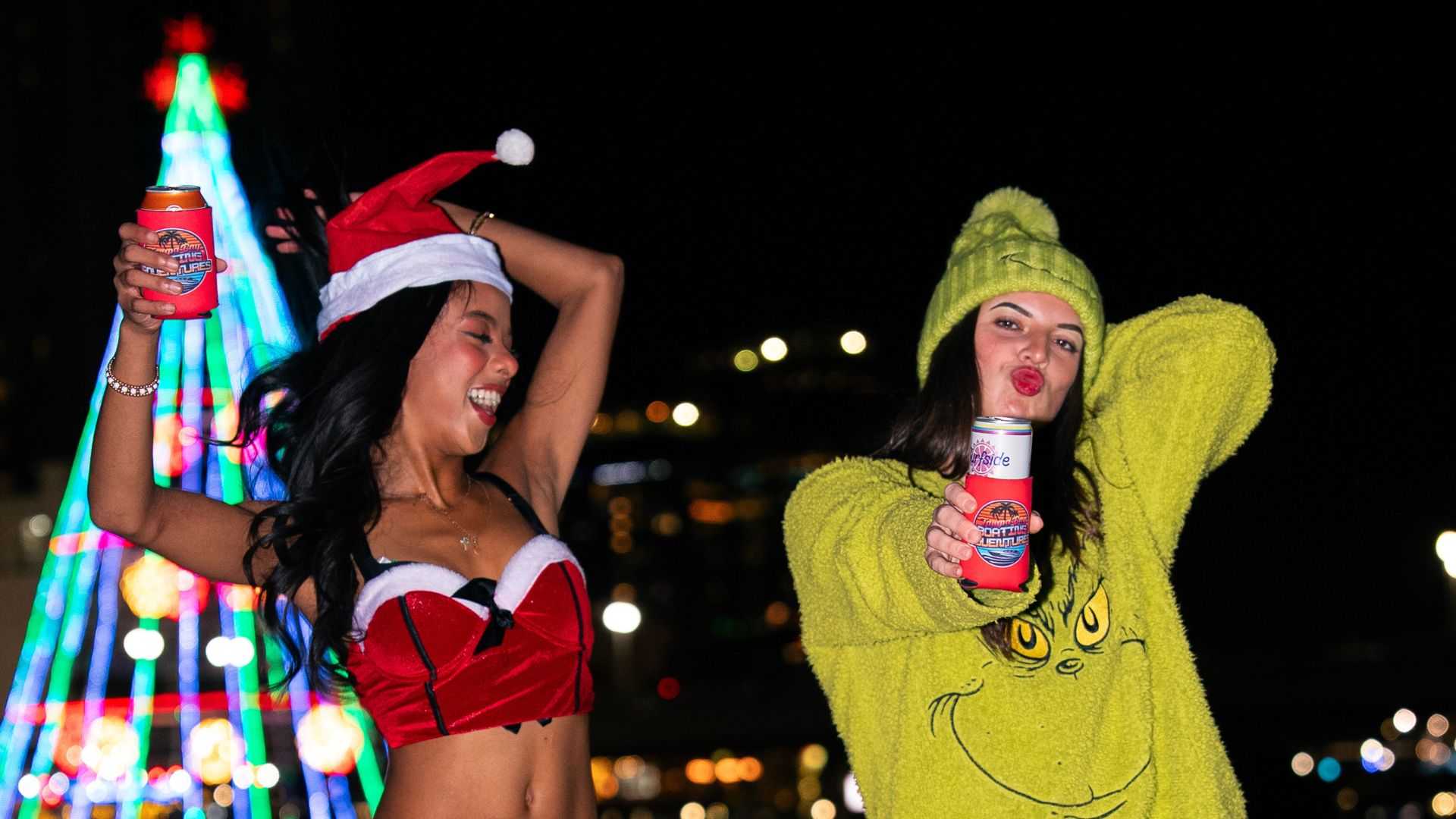 Guests dressed for a holiday boat night with a lit-up tree in the background.