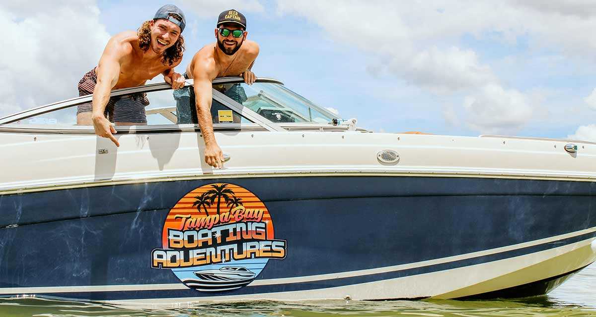 TBBA owners pointing at their party boat logo in Tampa Bay, FL.