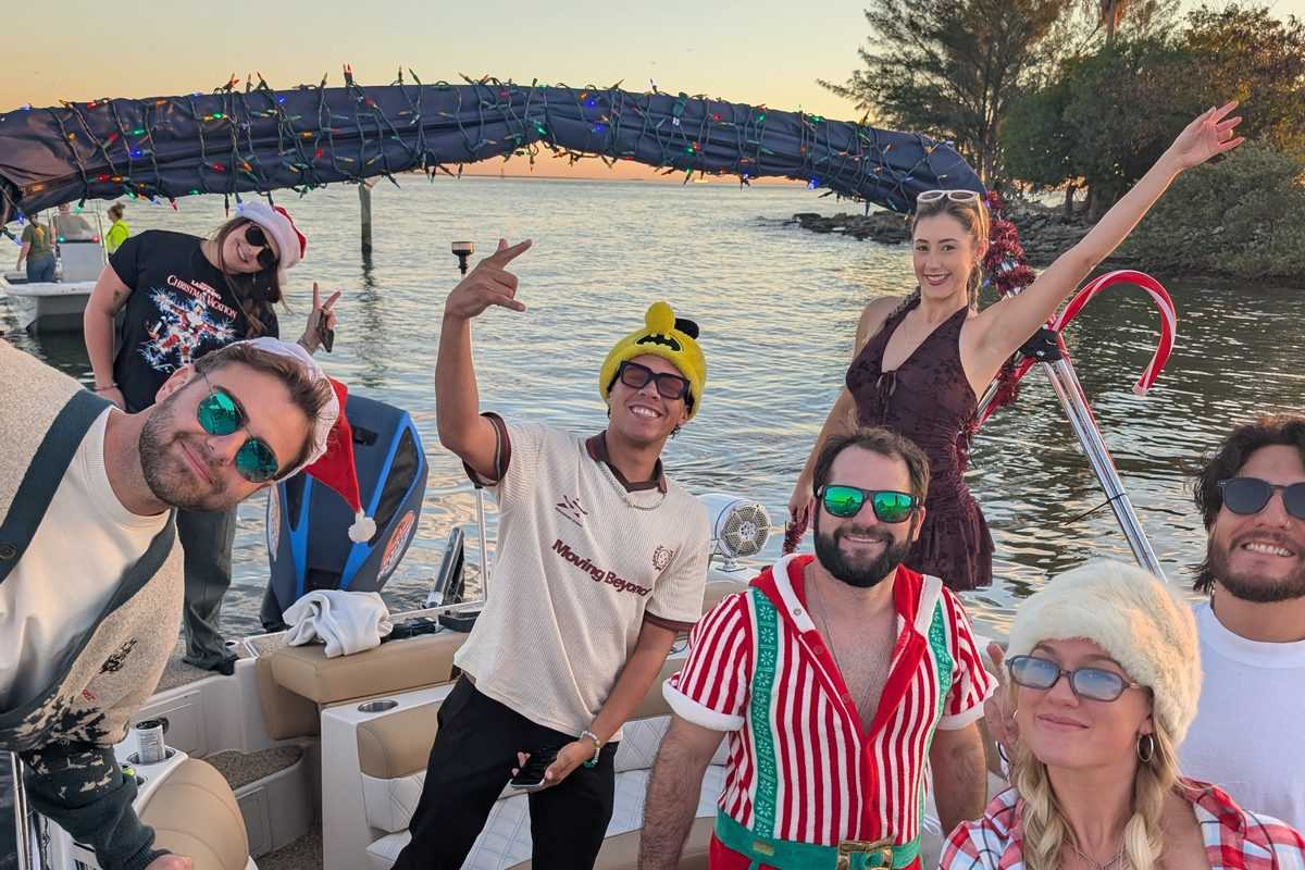 Group waving from the decorated boat at sunset.