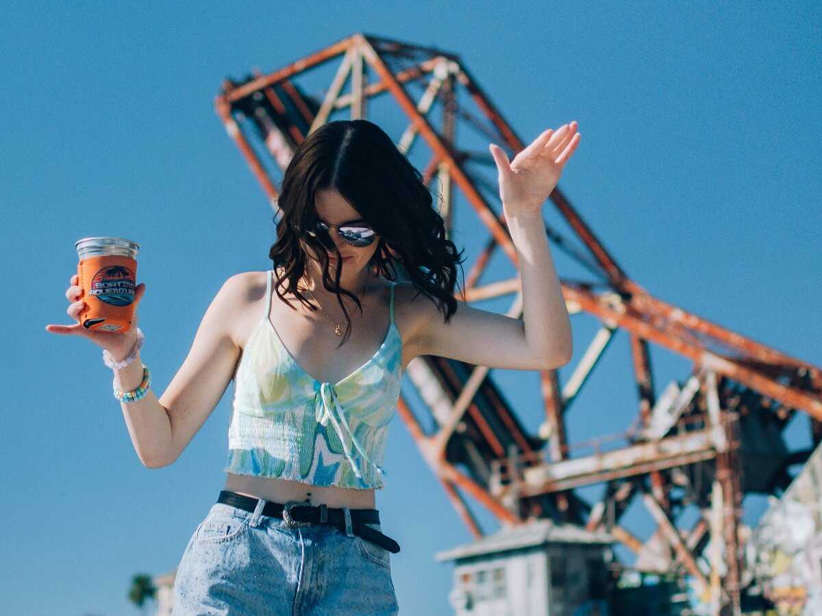 Guest waving with a drink in hand, University of Tampa in the background.