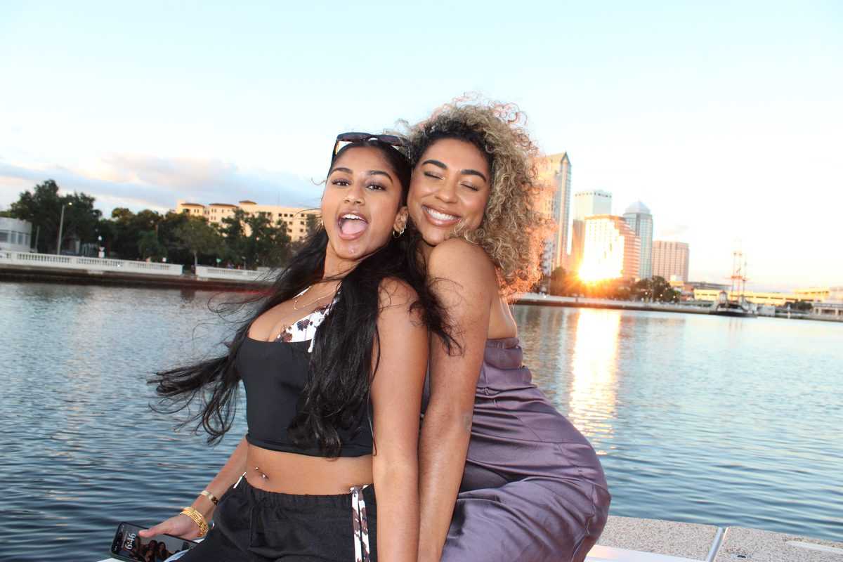 Friends laughing on the bow with the Tampa skyline at sunset.